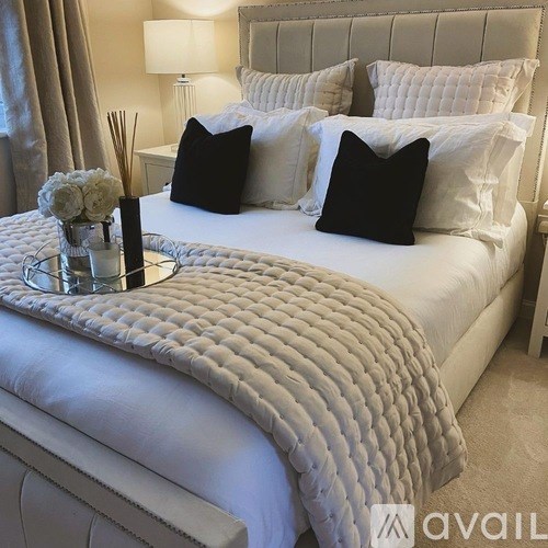 A bed with a white comforter and pillows with a round tray on top.