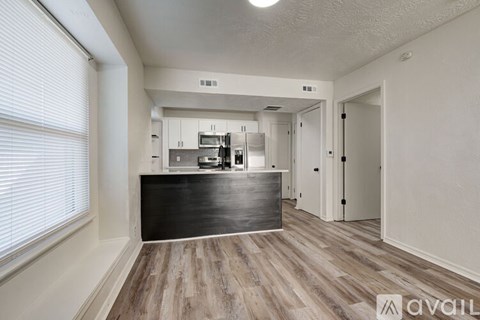 A spacious kitchen with white cabinets and a wooden floor.