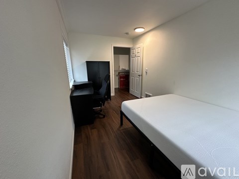 A bedroom with a bed, a desk with a computer, and a wardrobe.