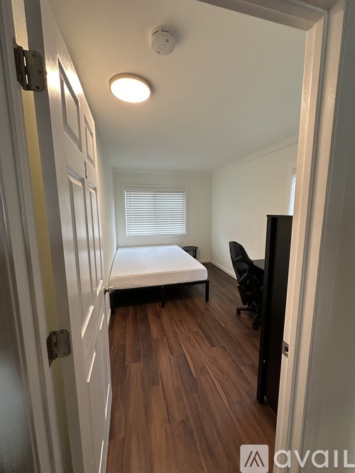 A bedroom with a bed, chair, and wooden floors.