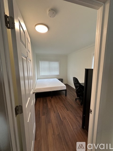 A bedroom with a bed, chair, and wooden floors.