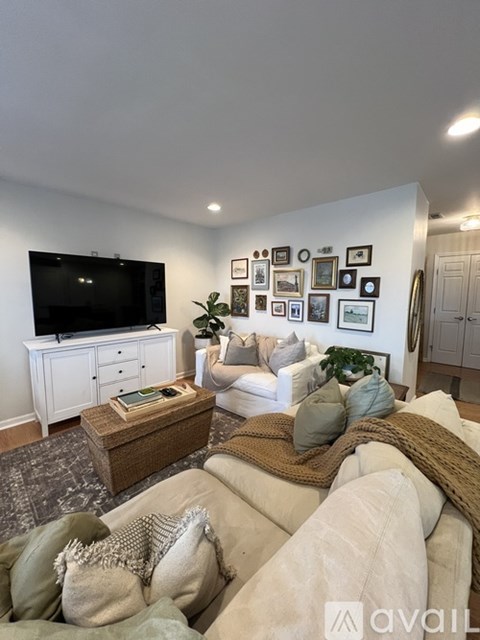 A living room with a white couch and a television on a cabinet.