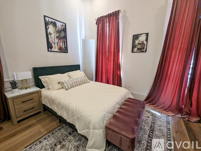 A bedroom with a large bed and red curtains.