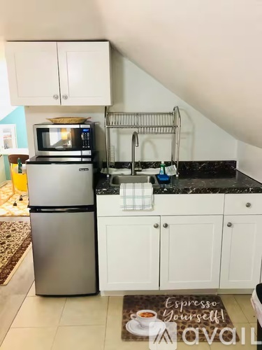 A kitchen with white cabinets and a black countertop.