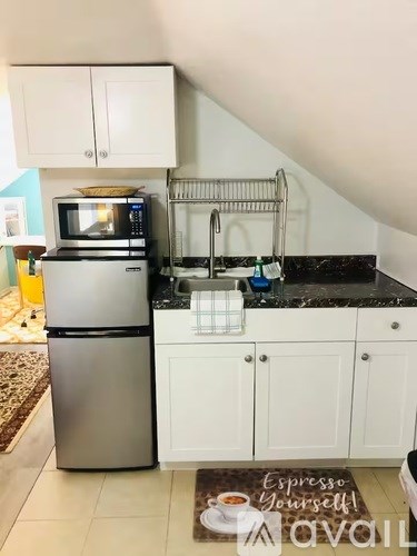 A kitchen with white cabinets and a black countertop.