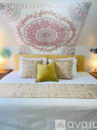 A bed with a yellow headboard and two green pillows.