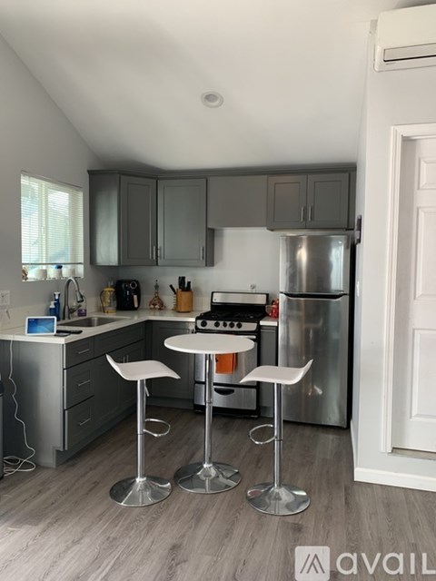 A kitchen with a refrigerator, stove, and two bar stools.