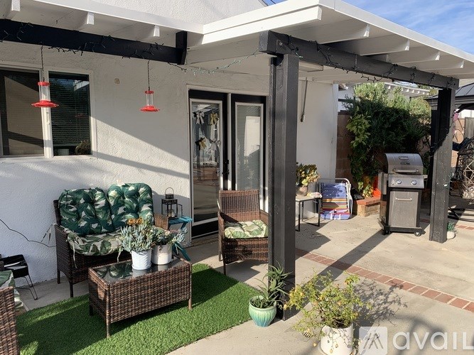 A patio with a couch, chairs, and a table with a vase of flowers on it.