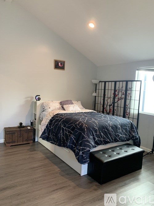 A bedroom with a bed, nightstand, and window.