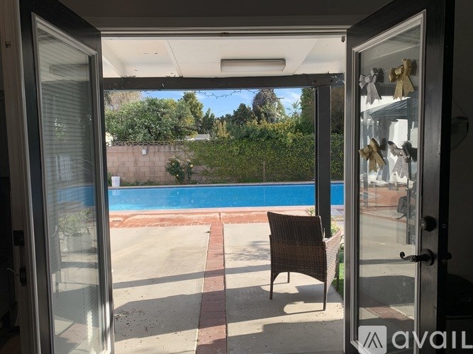 A patio with a chair and a pool in the background.