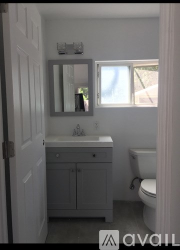 A bathroom with a toilet, sink, and mirror.