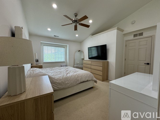 A bedroom with a bed, dresser, and a ceiling fan.