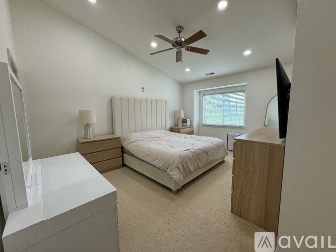 A bedroom with a bed, dresser, and television.
