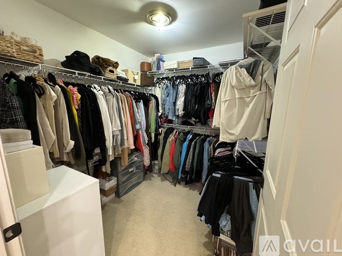 A white closet with clothes hanging on hangers.