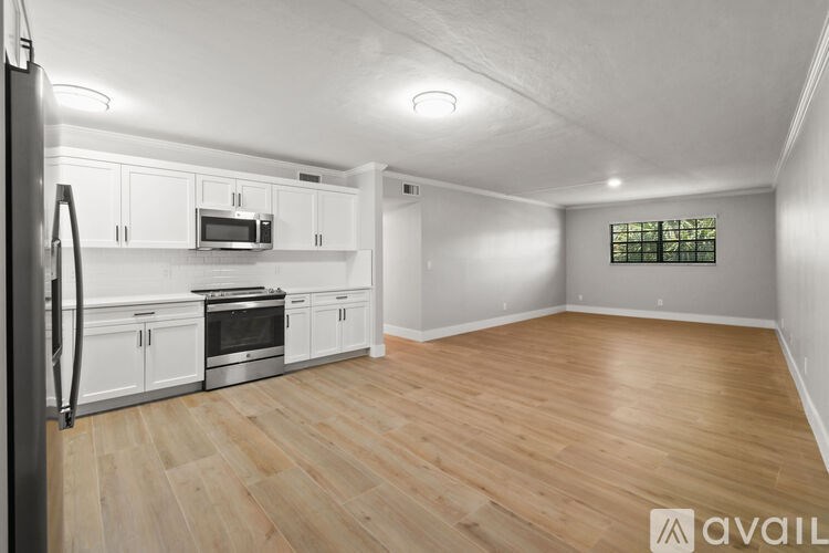 A kitchen with white cabinets and a refrigerator.