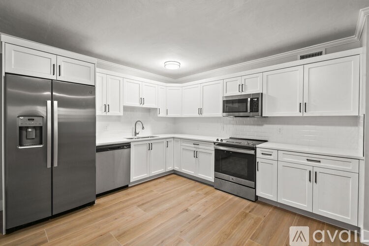 A kitchen with white cabinets and a stainless steel refrigerator.