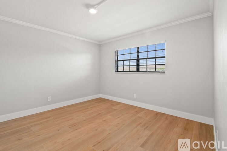 A room with wooden flooring and a window with bars on it.