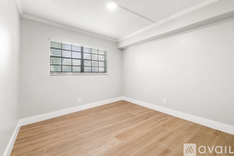 A room with wooden flooring and a window with blinds.