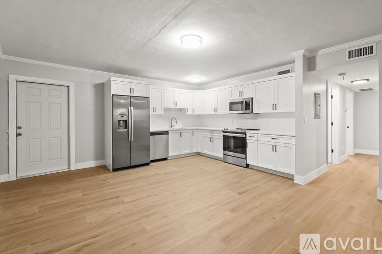 A kitchen with white cabinets and wooden floors.