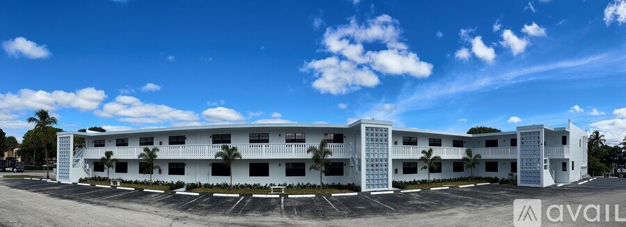 A large white building with multiple balconies and palm trees in front.
