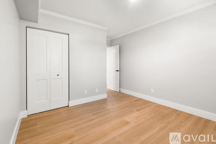 A room with a white door and a wooden floor.