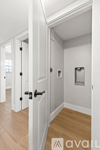 A hallway with a wooden floor and white walls.