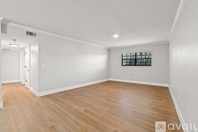 A room with wooden flooring and a window with bars on it.
