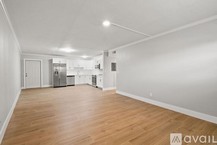 A spacious kitchen with white cabinets and a wooden floor.