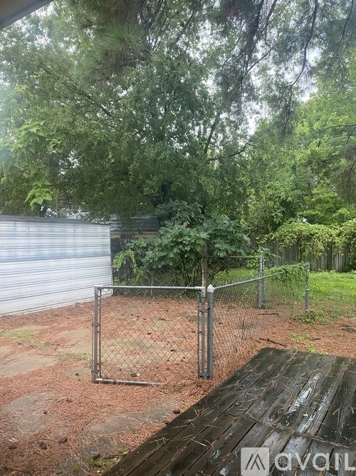 A wooden picnic table sits in front of a chain link fence.