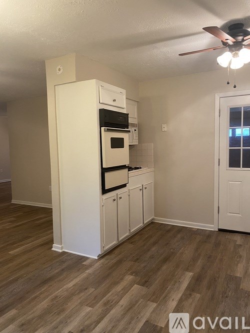 A kitchen with a white fridge and wooden floors.