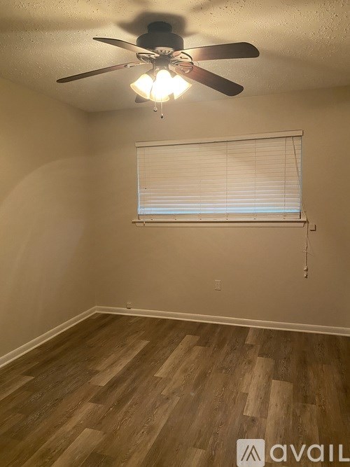 A room with a ceiling fan and a window with blinds.