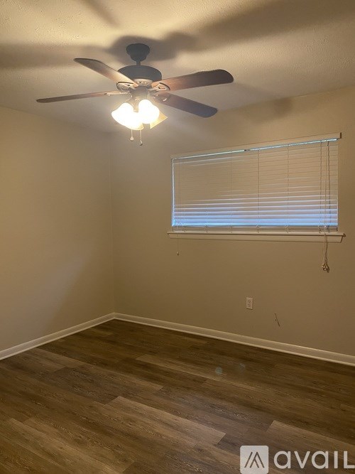 A room with a ceiling fan and a window with blinds.