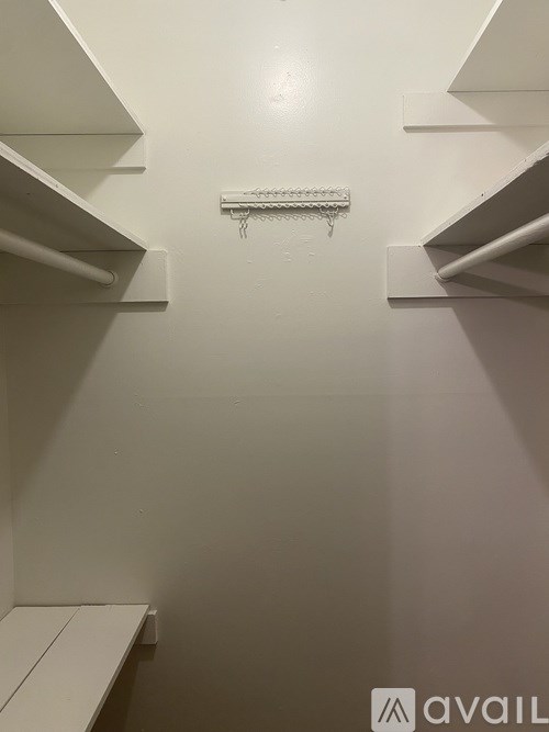 A white pantry with shelves and a white bench.