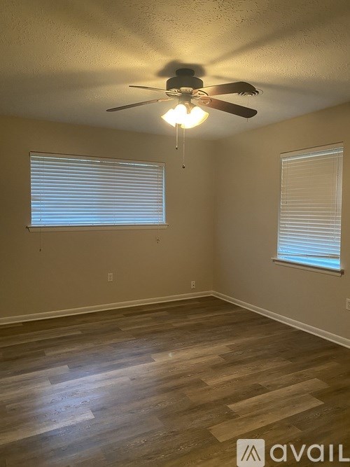 A room with a ceiling fan and two windows.