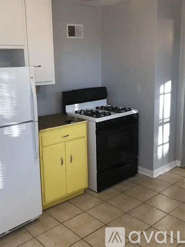 A kitchen with a white fridge, yellow cabinet, and black stove.