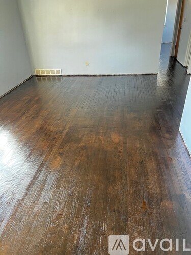A room with wooden flooring and a wall heater.