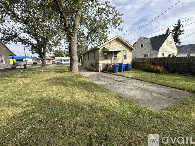 A backyard with a tree, a house, and a fence.