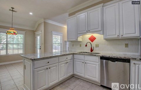 A kitchen with white cabinets and a black dishwasher.