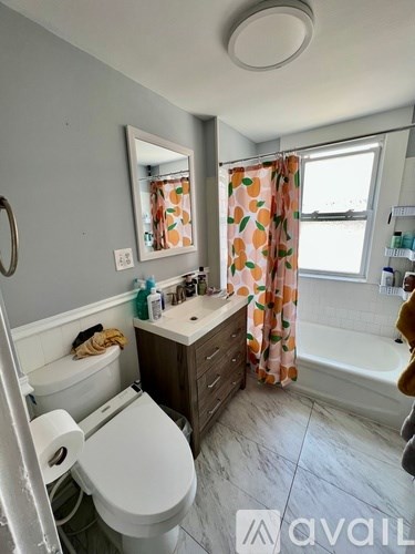 A bathroom with a toilet, sink, and a window with a curtain.