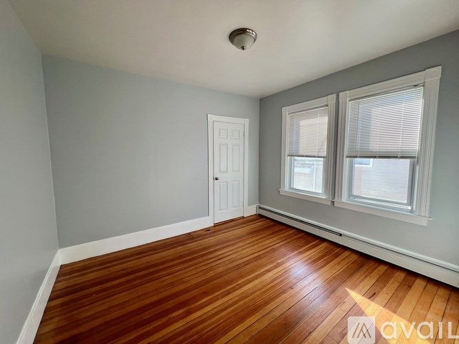 A room with wooden floors and two windows.