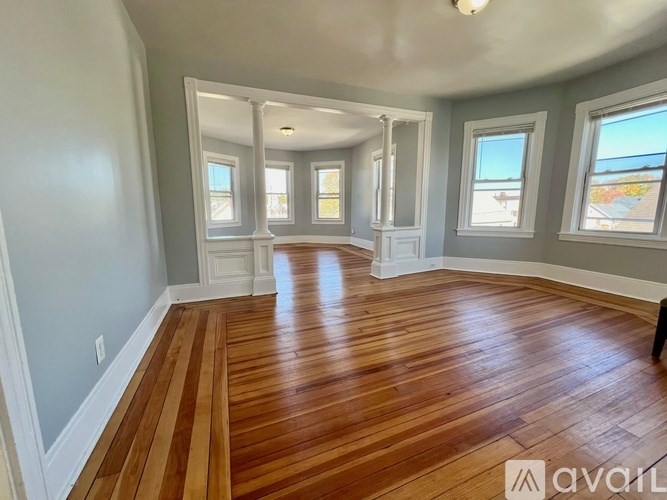 A room with wooden flooring and three windows.