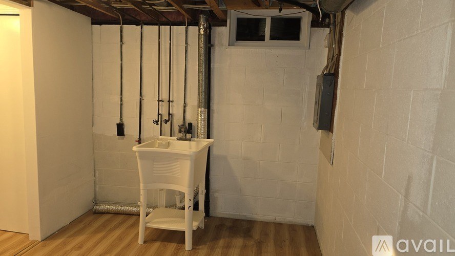 A white chair is placed in a room with a white wall and a white sink.