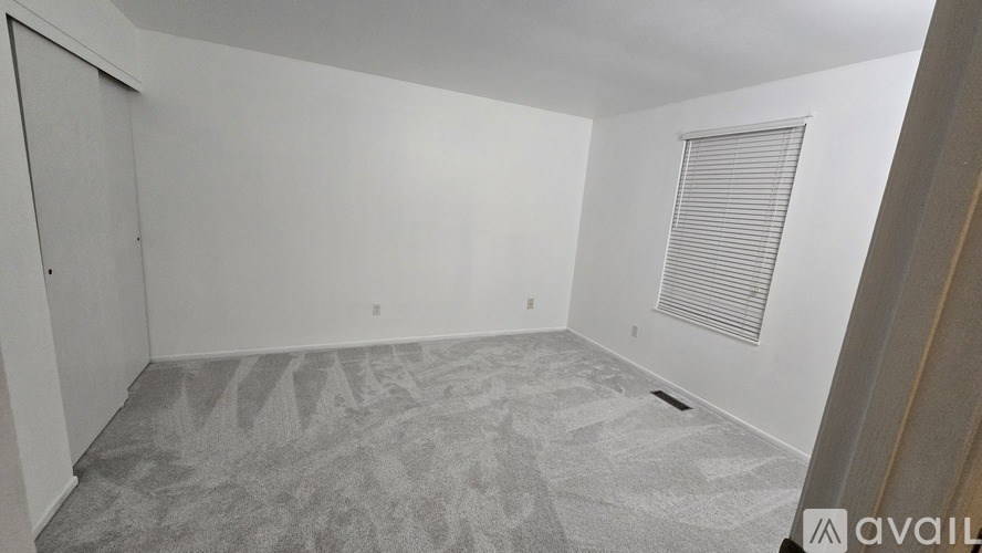 A room with a carpeted floor and a window with blinds.