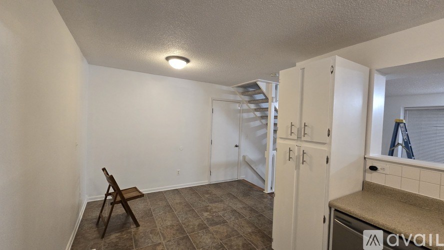 A room with a chair and a cabinet with a mirror above it.