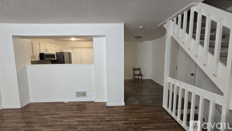 A room with a wooden floor and a staircase on the right side.