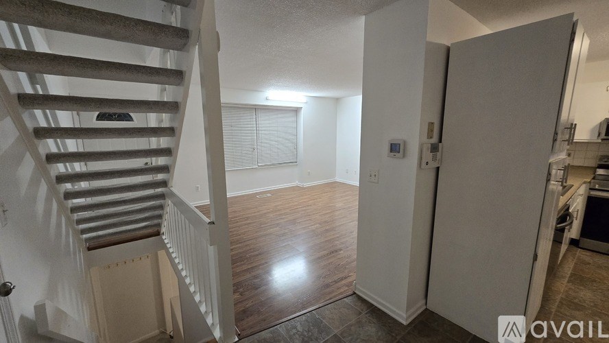 A room with a staircase and a door leading to a kitchen.