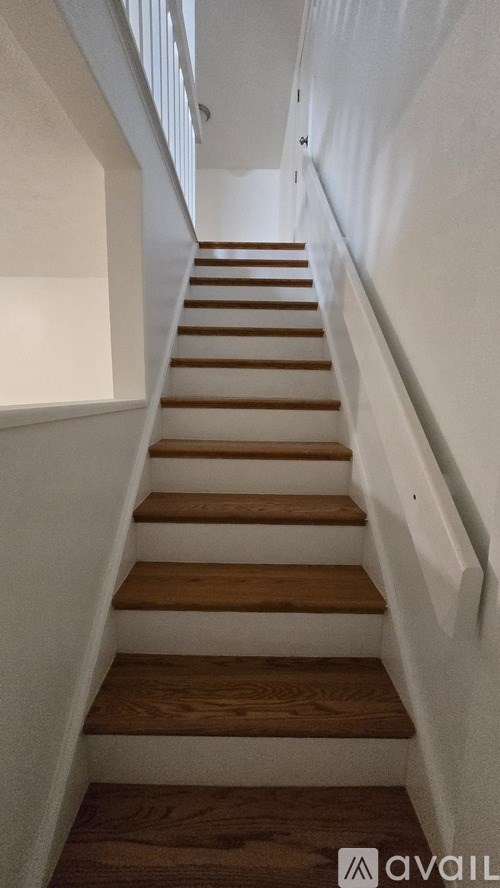 A staircase with wooden steps and white walls.