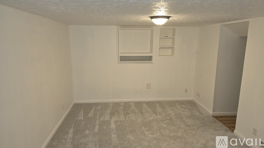 A room with a carpeted floor and a window with blinds.
