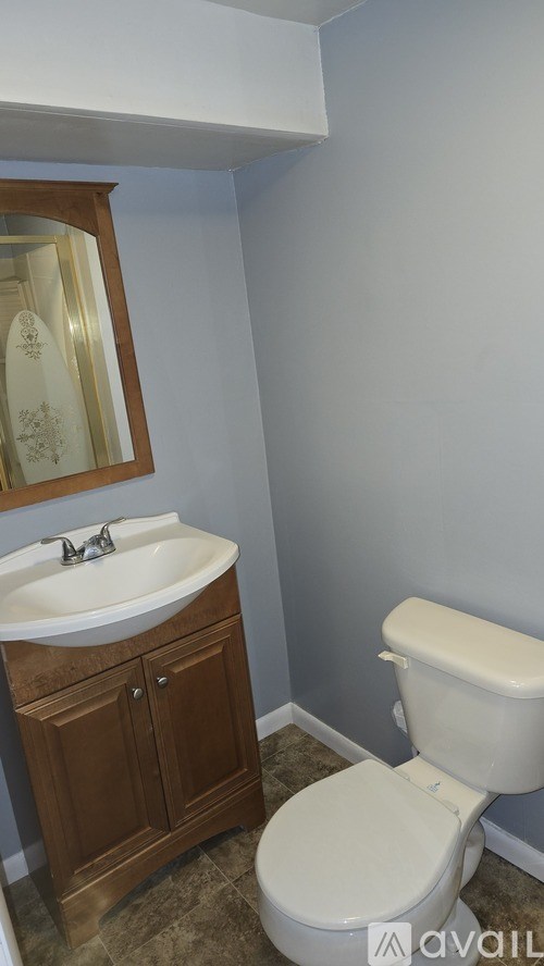 A bathroom with a toilet, sink and cabinet.