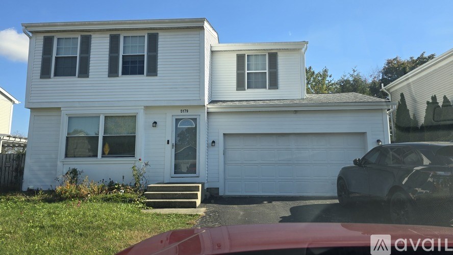 A two-story house with a garage and a car parked in front.